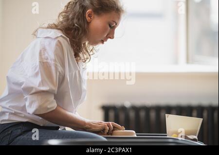 Potter makes the clay product with pottery modeling tools on the potter's wheel. Stock Photo