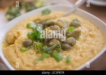 A bowl of traditional Greek Fava - Puree of Yellow split peas, served with Capers and scallion Stock Photo