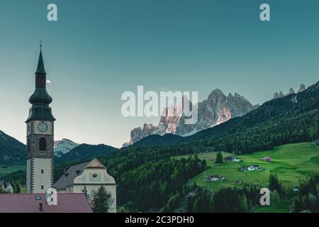 Beautiful view of church in Italian village San Pietro in Dolomites Alps at sunrise. Val di Funes, South Tyrol, Italy, Europe Stock Photo