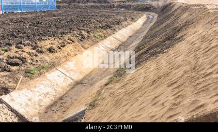 Construction of a drainage ditch along a road near an industrial facility Stock Photo