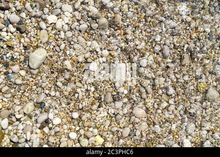 Colorful pebbles on a beach with clean water. Abstract background. Stock Photo
