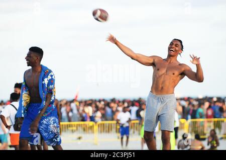 MIAMI - MARCH 15, 2019: Young men pass an American football at a gathering of college students celebrating spring break on South Beach. Stock Photo