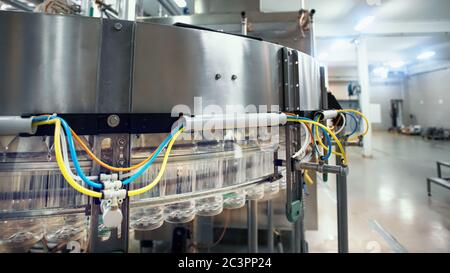 Production line of plastic bottles, conveyor line in beverage factory, manufacturing process, close up. Stock Photo