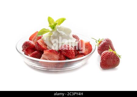 Fresh strawberries, whipped cream and peppermint garnish in a glass bowl, isolated with shadows on a white background, copy space Stock Photo