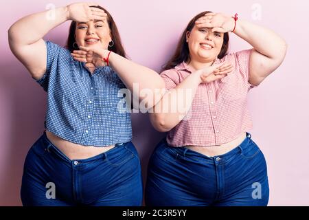 Young plus size twins wearing casual clothes smiling cheerful playing peek a boo with hands showing face. surprised and exited Stock Photo