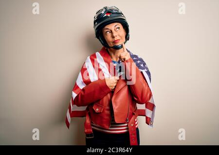 Middle age motorcyclist woman wearing motorcycle helmet and united states flag serious face thinking about question, very confused idea Stock Photo