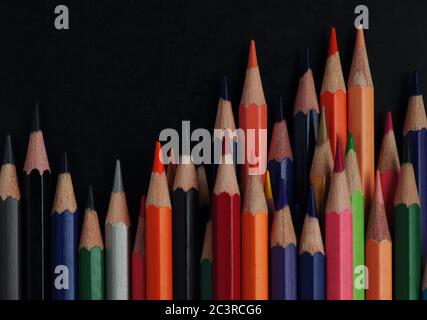 The large group of colored pencils on the black floor Stock Photo
