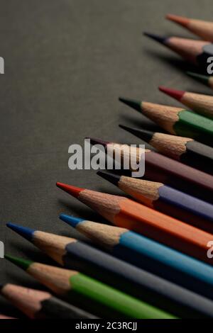 The large group of colored pencils on the black floor Stock Photo