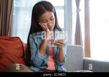peer pressure. young teenage asian girl feel depress while using her mobile phone at home Stock Photo
