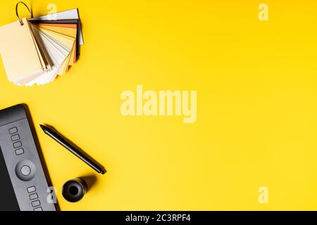 top view of drawing tablet, palette and color pencils near stylus on yellow Stock Photo