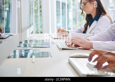 Medical laboratory researchers working on computers, entering data and analyzing statistics and results of medical tests Stock Photo