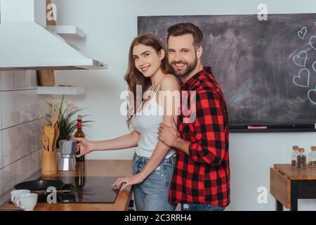 happy young couple smiling at camera while making coffee in geyser coffee maker Stock Photo