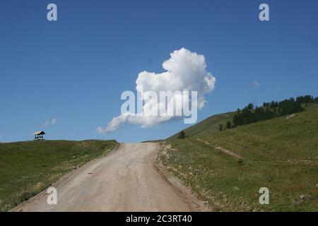 Beautiful cloud over the road on a blue sky in summer in the Altai mountains. Siberia. Landscape. Journey Stock Photo