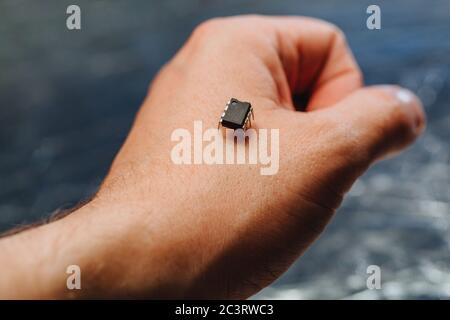 Implantation of a small black chip in hand. Future technology of chipization people for observation in social crisis time. Restriction of freedom. Stock Photo