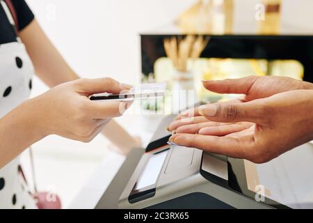 Close-up image of female customer giving credit card to bakery shop owner to pay for the order Stock Photo