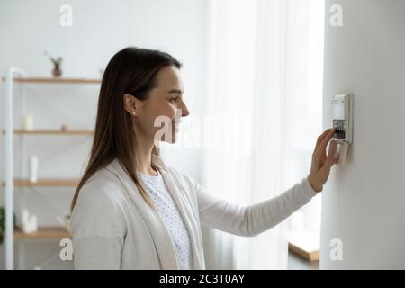 Smiling woman adjusting degrees set comfortable temperature using thermostat Stock Photo