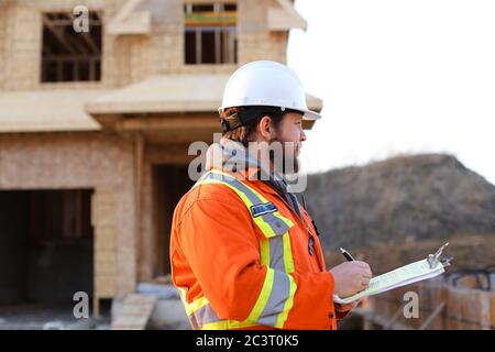 European foreman writing in notebook on construction site. Stock Photo