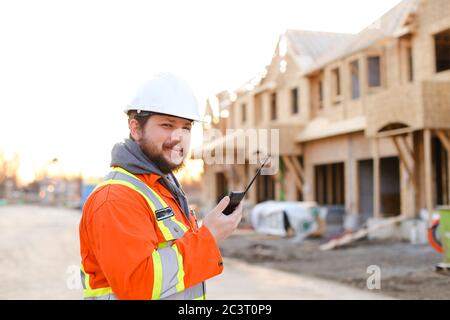Portrait of european engineer talking by walkie talkie on construction site. Stock Photo