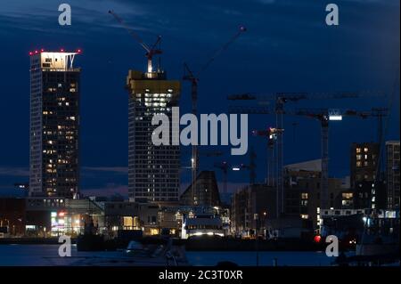 A night city skyline view of modern residential district with two skyscrapers against vivid blue sky. Stock Photo