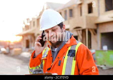 Portrait of foreman talking by smartphone on construction site. Stock Photo