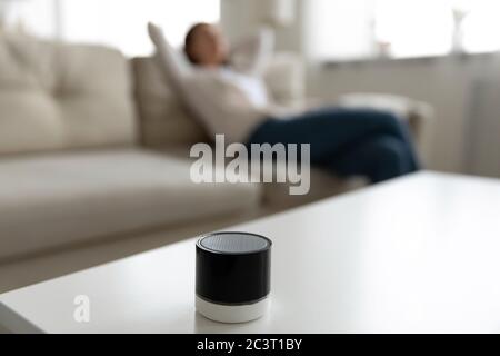 Woman listening music using mini portable speaker located on table Stock Photo