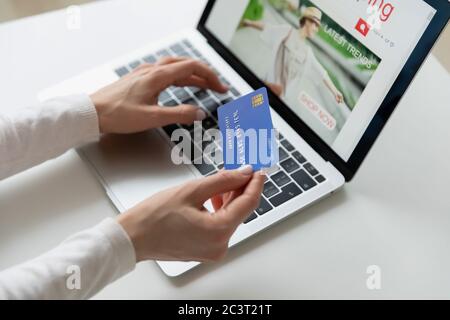 Closeup female hands holds credit card makes payment using laptop Stock Photo