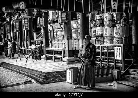 Monk in traditional robes standing in front of altar, Kitano Tenmangu shinto shrine, Kyoto, Japan Stock Photo