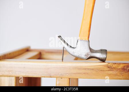 Close-up image of builder using hammer to pull nail out of wooden board Stock Photo