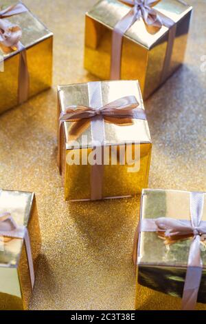 Group of gold sparkling gift boxes, beautiful gold packaging surprise with bow on sparkling background Stock Photo