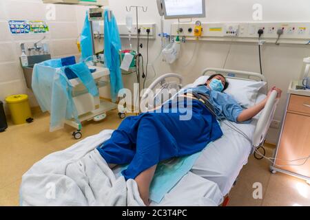 Kota Kinabalu, Sabah, Malaysia-May 30, 2020 : Young Asian Chinese lady in Contraction pain on hospital labour room ward bed waiting to delivery newbor Stock Photo
