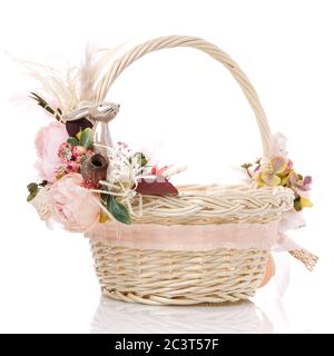 Easter basket on white background. Decorated with pink flowers and a small decorative ceramic hare. Ribbons and lace. Stock Photo