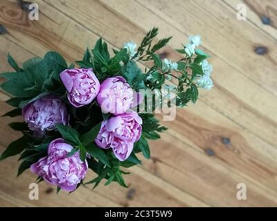 Bouquet of fresh pink peonies. Bouquet of peonies flower on a wooden background. Top view, flat lay. Stock Photo