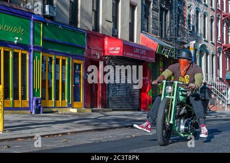 Man riding a Triumph motorcycle motorbike in East Village, alphabet city Emergency staris fire scape. New York. Alphabet City Apartments.  House with Stock Photo