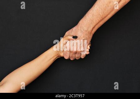 Support concept, a man's hand pulling up a woman's hand. photo isolate on black background Stock Photo
