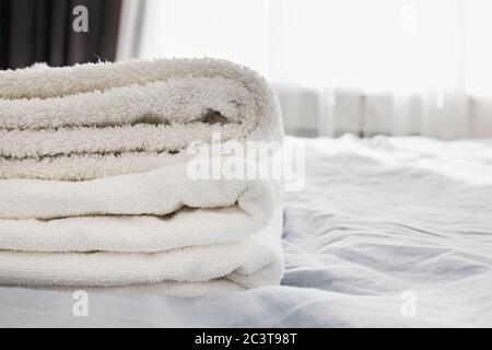Pile of clean white towels on the bed Stock Photo