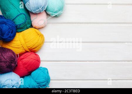 Bright colorful clews and crochet hooks on light wooden background Stock Photo