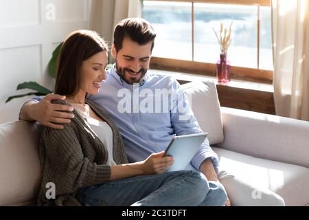 Smiling woman and man hugging, using electronic device together Stock Photo
