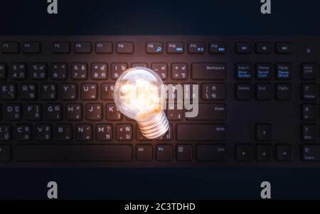 Glowing light bulb on computer keyboard Stock Photo
