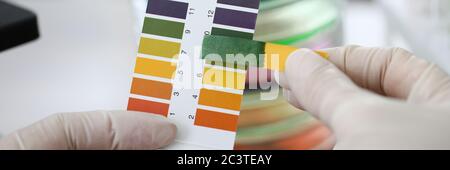 Close-up gloved hands holding litmus indicator Stock Photo
