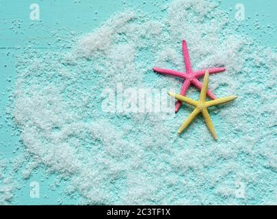 Two beautiful colored starfish lie on artificial sea foam on turquoise wooden background. Place for text. Banner template. Stock Photo