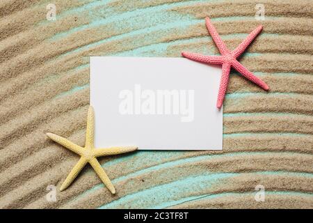 White blank card for text with starfish on sand on turquoise background. Wavy textured sand. Stock Photo