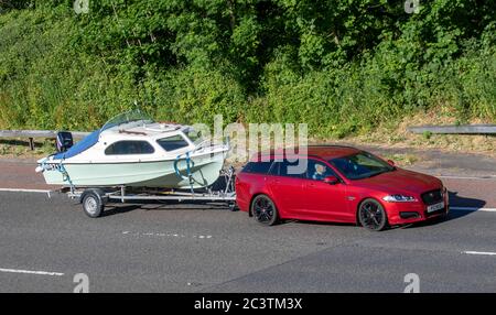 2015 red Jaguar XF R-Sport Black D Auto estate towing speedboat; Vehicular traffic moving vehicles, cars driving vehicle on UK roads, motors, motoring on the M6 motorway Stock Photo
