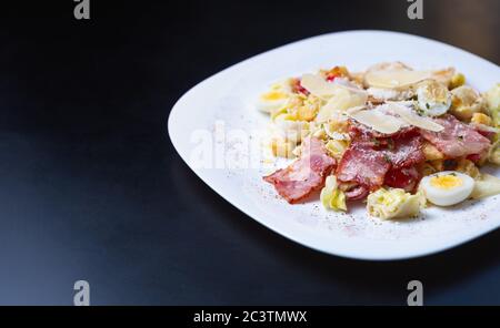 Delicious caesar salad on table with empty space for text.Gourmet Italian food cooked with natural ingredients:boiled quail eggs,parmesan cheese,fried Stock Photo
