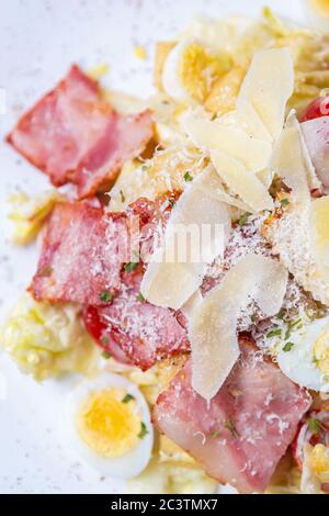 Gourmet caesar salad shot directly from above in restaurant.Delicious Italian snack food with natural ingredients:parmesan cheese,bacon meat strips,qu Stock Photo