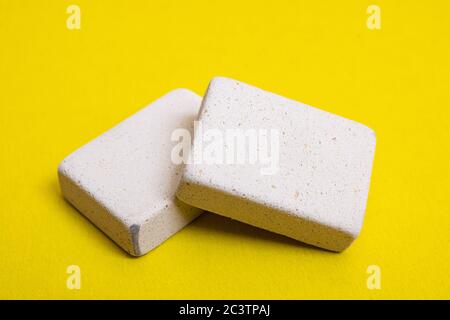 Two pencil erasers on a yellow background close up Stock Photo