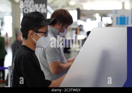 Passengers using check-in machines while wearing face masks as a preventive measure at Chubu Centrair International Airport.Japan's government lifted all COVID-19 related restrictions on domestic travels on June 19 while most of the international flights remain cancelled. Stock Photo