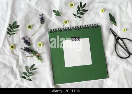 Summer lifestyle floral composition. Green diary, sketch book mockup scene with blank memo pad. Lavender and chrysanthemum flowers and green leaves on Stock Photo