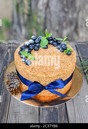 layer cake Napoleon with berries of blueberry on a rough wooden backgound sprinkled with powdered sugar Stock Photo
