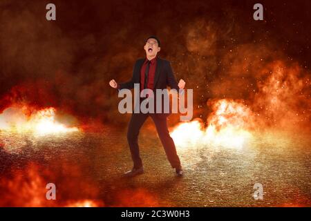 Asian businessman standing with emotional expression with an explosion and smoke background Stock Photo