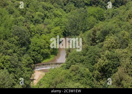 Dam on river in forest below the medieval hill town of Pitigliano, Tuscany, Italy Stock Photo